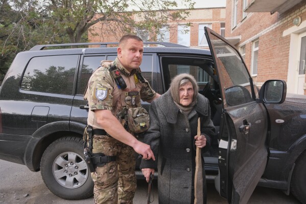 In this photo provided by the Ukrainian National Police of Donetsk region, 98-year-old Lidia Lomikovska is helped by a Ukrainian police officer after she escaped Russian-occupied territory in the Donetsk region, Ukraine, April 26, 2024. Lomikovska left the frontline town of Ocheretyne last week by walking almost 10 km (6 miles) alone, after Russian troops entered it and fighting intensified. (Ukrainian National Police of Donetsk region via AP)