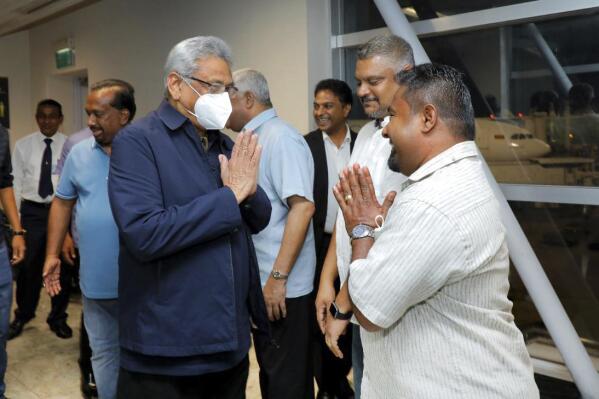In this handout picture provided by the Ministry of Urban Development and Housing of Government of Sri Lanka, Sri Lanka's former President Gotabaya Rajapaksa, wearing mask, is greeted upon his arrival at Bandaranaike International airport in Colombo, Sri Lanka, Saturday, Sept. 3, 2022. Gotabaya Rajapaksa, who fled the country in July after tens of thousands of protesters stormed his home and office in a display of anger over the country's economic crisis, has returned to the country after seven weeks. (Ministry of Urban Development and Housing of Government of Sri Lanka via AP Photo)