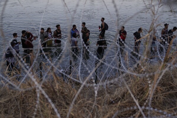 Migrants wait to climb over concertina wire after they crossed the Rio Grande and entered the U.S. from Mexico, Sept. 23, 2023, in Eagle Pass, Texas. (AP Photo/Eric Gay, File)