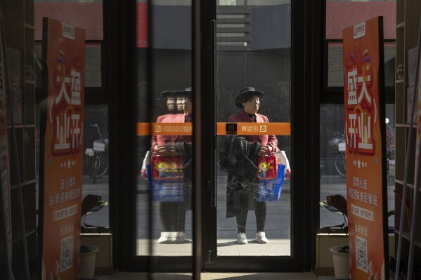 An elderly woman stands at the entrance to the University for the Elderly in Beijing, Oct. 23, 2024. (AP Photo/Ng Han Guan)