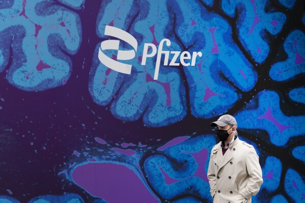 FILE - A man walks by Pfizer headquarters, Friday, Feb. 5, 2021, in New York. Pfizer reports earnings on Tuesday, Oct. 31, 2023. (AP Photo/Mark Lennihan, File)