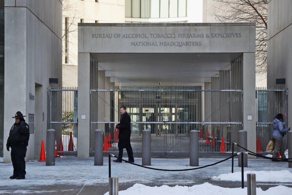 FILE - In this Thursday, Jan. 23, 2014 photo, a security official walks in front of the entrance to the national headquarters of the Bureau of Alcohol, Tobacco, Firearms and Explosives in Washington. On Friday, March 1, 2024, The Associated Press reported on stories circulating online incorrectly claiming an update to the Bureau of Alcohol, Tobacco, Firearms and Explosives’ background check policy allows people in the U.S. illegally to purchase firearms. (AP Photo/Charles Dharapak, File)