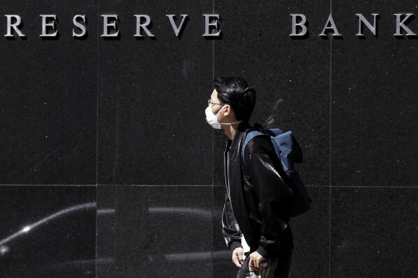 FILE - A man wearing a mask goes past the Reserve Bank of Australia in Sydney, on March 19, 2020. Australia’s central bank on Tuesday, Aug. 1, 2023, left its benchmark interest rate on hold at 4.1% for a second consecutive month raising expectations that rates might have reached their peak or are close to plateauingor be close to the plateau of the current cycle. (AP Photo/Rick Rycroft, File)