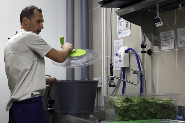 Pierre Bigot, a local sous chef, dries spinach in the kitchen of the United States Olympic and Paralympic Committee's High Performance Center's kitchen on Saturday, Aug. 31, 2024. The USOPC brought in staff from Colorado and also hired local chefs to work in the kitchen. (AP Photo/Nathalee Simoneau)