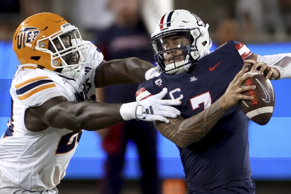 Arizona quarterback Jayden de Laura (7) manages to get away from a UTEP defender during an NCAA college football game between UTEP and Arizona on Saturday, Sept. 16, 2023, in Tucson, Ariz. (Kelly Presnell/Arizona Daily Star via AP)