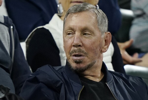 FILE - Larry Ellison, chairman of Oracle Corporation and chief technology officer, watches from the stands at the BNP Paribas Open tennis tournament Oct. 13, 2021, in Indian Wells, Calif. The world could have its first trillionaire within a decade, anti-poverty organization Oxfam International said Monday Jan. 15, 2024 in its annual assessment of global inequalities timed to the gathering of political and business elites at the Swiss ski resort of Davos. (AP Photo/Mark J. Terrill, File)