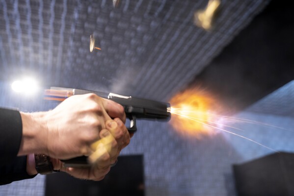 A semi-automatic pistol with a conversion device installed making it fully automatic is fired as four empty shell casings fly out of the weapon, at the Bureau of Alcohol, Tobacco, Firearms, and Explosives (ATF), National Services Center, Thursday, March 2, 2023, in Martinsburg, W.Va. (AP Photo/Alex Brandon)