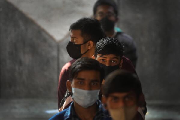 Children wait to receive their COVID-19 vaccination at a government school in New Delhi, India, Monday, Jan. 3, 2022. Indian health authorities Monday began vaccinating teens in the age group of 15 to 18, as more states started to enforce tighter restrictions to arrest a new surge stoked by the infectious omicron variant. (AP Photo/Manish Swarup)