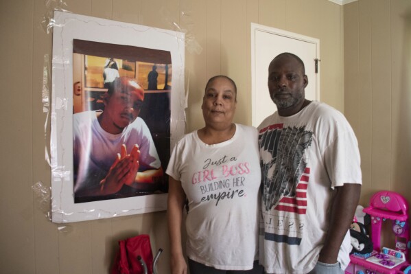 Keyana Gaines and her husband, Kenyatta Crawford, stand next to a photo of Gaines' son, Jermaine Jones Jr., at their home in Augusta, Ga., on April 16, 2023. Jones was one of at least 30 people in Georgia who died after encounters with police that did not involve firearms from 2012 through 2021. (Paige Maizes/Howard Center for Investigative Journalism via AP)