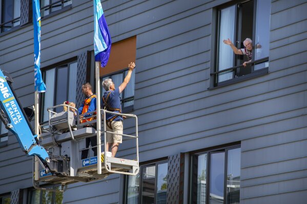 Pitrik van der Lubbe waves from a crane to his 88-year-old father Henk, right, whom he has not seen in over 4 weeks at nursing home Hanepraij in Gouda, Netherlands, Friday, April 24, 2020. The crane was made available for free by a company to allow family members to see their loved ones in isolation because of the coronavirus. (AP Photo/Peter Dejong)