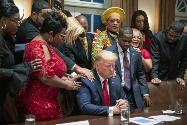 FILE - In this Thursday, Feb. 27, 2020, file photo, African American leaders say a prayer with President Donald Trump as they end a meeting in the Cabinet Room of the White House, in Washington. Trump’s appeal to religious conservatives is a cornerstone of his political identity. But Joe Biden is a different kind of foe than Trump has faced before: one who makes faith a central part of his persona – often literally wearing it on his sleeve. (AP Photo/Manuel Balce Ceneta, File)