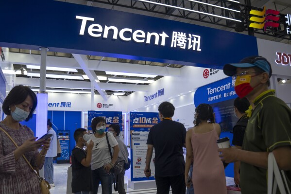 FILE - Visitors gather near a booth for Chinese technology firm Tencent at the China International Fair for Trade in Services (CIFTIS) in Beijing, on Sept. 3, 2022. China released draft guidelines Friday, Dec, 22, 2023, aimed at curbing excessive spending on online gaming in the latest move by the ruling Communist Party to keep control of the virtual economy. The proposal caused shares in the biggest Chinese gaming companies, Tencent and NetEase, to plunge in Hong Kong. (AP Photo/Mark Schiefelbein, File)