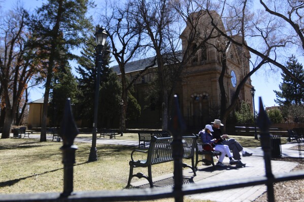 People walk around the Santa Fe Plaza in Santa Fe, New Mexico, Friday, Feb. 28, 2025. (AP Photo/Ty O'Neil)