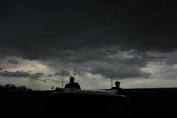 Victor Gensini, Northern Illinois University meteorology professor and a lead scientist of Project ICECHIP, right, and Logan Bundy, PhD Candidate at NIU and ICECHIP IOP assistant, left, stand at the command vehicle watching an approaching storm Tuesday, June 3, 2025, in Scotland, Texas. (AP Photo/Carolyn Kaster)