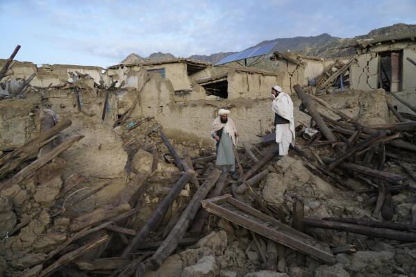 Afghans stand among destruction after an earthquake in Gayan village, in Paktika province, Afghanistan, Thursday, June 23, 2022. A powerful earthquake struck a rugged, mountainous region of eastern Afghanistan early Wednesday, flattening stone and mud-brick homes in the country's deadliest quake in two decades, the state-run news agency reported. (AP Photo/Ebrahim Nooroozi)