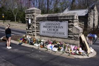 FILE - A woman pauses as she visits a memorial at the entrance to The Covenant School, March 29, 2023, in Nashville, Tenn. A group of Tennessee parents whose children attend The Covenant School, where a deadly shooting in March took the lives of three 9-year-olds and three adults, filed a motion on Wednesday, May 17, seeking to keep the shooter's writings from being released to the public. (AP Photo/Wade Payne, File)