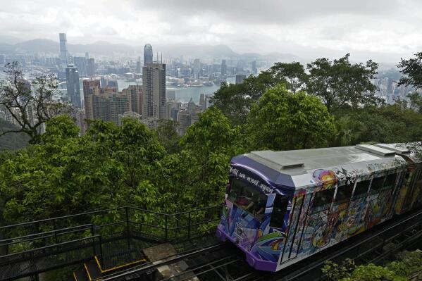 A Peak Tram passes an uphill of the Victoria Peak with a backdrop of Hong Kong on June 17, 2021. Hong Kong’s Peak Tram is a fixture in the memories of many residents and tourists, ferrying passengers up Victoria Peak for a bird’s eye view of the city’s many skyscrapers. (AP Photo/Vincent Yu)