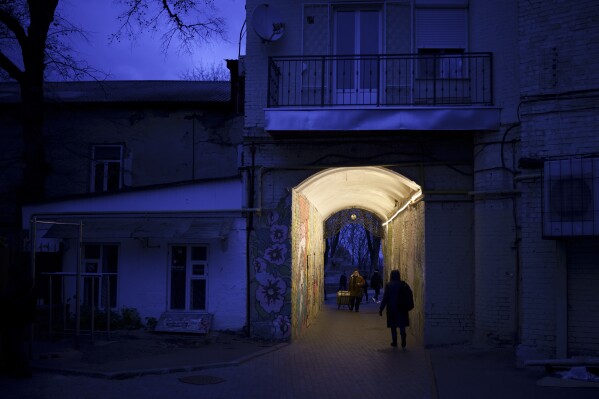 People walk through an alleyway at dusk in central Kyiv, Ukraine, Saturday, Nov. 18, 2023. (AP Photo/Felipe Dana)