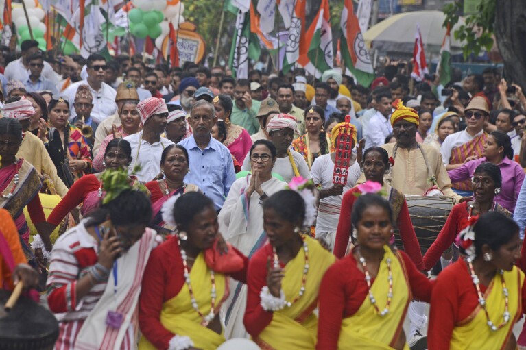 Trinamool Congress leader Mamata Banerjee, center, greets as she walks with tribal people during an election campaign rally for the national elections, in Siliguri, India, Tuesday, April 16, 2024.(AP Photo/Diptendu Dutta)