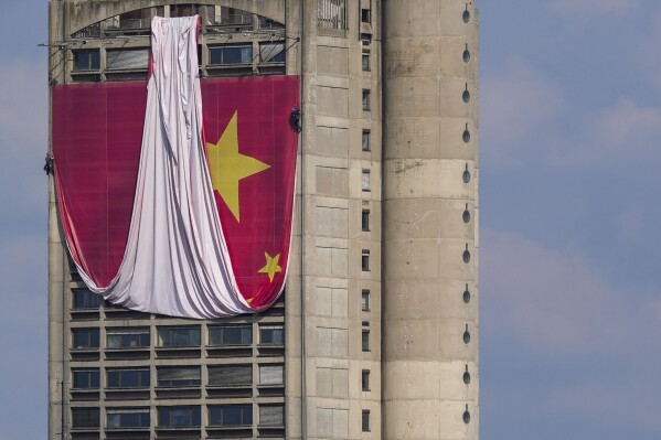 Workers hang on ropes to install a giant Chinese national flag on a skyscraper that is a symbolic gateway leading into the city from the airport, in Belgrade, Serbia, Saturday, May 4, 2024. Chinese leader Xi Jinping's visit to European ally Serbia on Tuesday falls on a symbolic date: the 25th anniversary of the bombing of the Chinese Embassy in Belgrade during NATO's air war over Kosovo. (AP Photo/Darko Vojinovic)