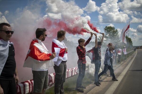 FILE - Protesters, some of them are ethnic Belarusian, light flares as they attend a protest demanding freedom for political prisoners in Belarus near Medininkai village near Lithuanian-Belarusian, Lithuania, Saturday, June 12, 2021. Lithuania on Wednesday, Aug. 16, 2023 decided to temporarily close two of its six checkpoints with Belarus later this week amid growing tensions with its eastern neighbor, an ally of Russia. The Lithuanian government has said that the crossings at Tverecius and Sumskas will be closed, and traffic will be diverted to the Medininkai border checkpoint, which is the largest of Lithuania’s six checkpoints. (AP Photo/Mindaugas Kulbis, file)