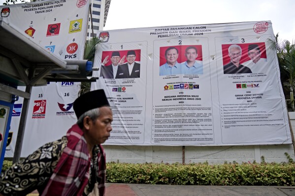 A street vendor pulls his cart past an election banner introducing presidential candidates, from left, Anies Baswedan and his running mate Muhaimin Iskandar, Prabowo Subianto and his running mate Gibran Rakabuming Raka, the eldest son of Indonesian President Joko Widodo, and Ganjar Pranowo and his running mate Mahfud MD, in Jakarta, Indonesia, Thursday, Feb. 1, 2024. When millions of Indonesians pick their new president in one of the world's biggest elections on Feb. 14, the United States and China would be closely watching who will next lead a key Asian battleground coveted for its huge market, nickel and voice. (AP Photo/Dita Alangkara)