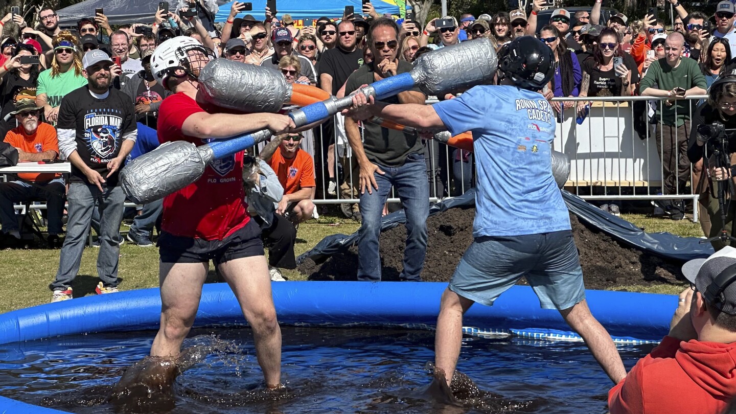 Competitors battle in a muddy pool with weapons made from pool noodles at the Florida Man Games on Saturday, Feb. 24, 2024, in St. Augustine, Fla. (AP Photo/Russ Bynum)