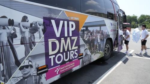 A banner advertising DMZ tour is attached at a tourist bus at the Imjingak Pavilion in Paju, South Korea, near the border with North Korea, Wednesday, July 19, 2023. North Korea was silent about the highly unusual entry of an American soldier across the Koreas' heavily fortified border although it test-fired short-range missiles Wednesday in its latest weapons display. (AP Photo/Ahn Young-joon)