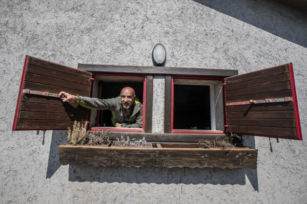 In this image take on Friday, April 24, 2020 Claudio Trentani, 57, opens a window of his shelter 'Baita Cassinelli' (1568 Mt.), at the foot of Mt. Presolana, in Castione della Presolana, near Bergamo, northern Italy. Of the COVID-19 pandemic he says, “It is a powerful tragedy that has touched chords that not even during the war had been touched.”  (AP Photo/Luca Bruno),