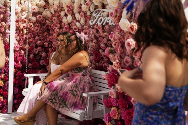 Race fans sit among flowers at Churchill Downs before the 151st running of the Kentucky Oaks horse race Friday, May 2, 2025, in Louisville, Ky. (AP Photo/Brynn Anderson)