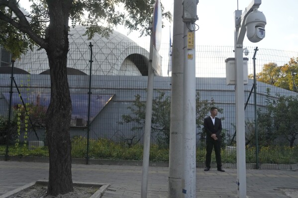 A plainclothes security person stand watch outside the Israeli Embassy in Beijing, Friday, Oct. 13, 2023. An employee of the Israeli Embassy in Beijing has been attacked and was later hospitalized, according to a statement from Israel's Foreign Ministry on Friday. (AP Photo/Ng Han Guan)