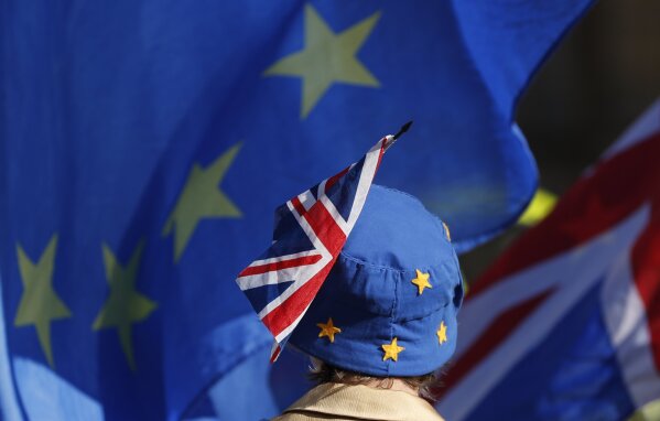 FILE - In this Oct. 16, 2018, file photo, a pro-EU demonstrator wears an EU flag styled as a hat, with a British Union flag pinned to it in London. With Brexit due on Oct. 31, 2019 and a costly no-deal a possible outcome, experts still do not know, or are reluctant to say, exactly what checks are likely at the Irish border. Nevertheless, British Prime Minister Boris Johnson remains convinced that a Brexit deal can be sealed with the EU in a few weeks. (AP Photo/Alastair Grant, File)