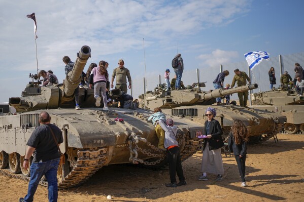 Israelis stand on tanks during an event for families of reservists outside a military base in southern Israel, Tuesday, Feb. 27, 2024. Israel and Hamas are inching toward a new deal that would free some of the roughly 130 hostages held in the Gaza Strip in exchange for a weeks-long pause in the war, now in its fifth month. A deal would bring some respite to desperate people in Gaza, who have borne a staggering toll in the war, as well as to the anguished families of hostages taken during Hamas' Oct. 7 attack that sparked the war. (AP Photo/Ohad Zwigenberg)