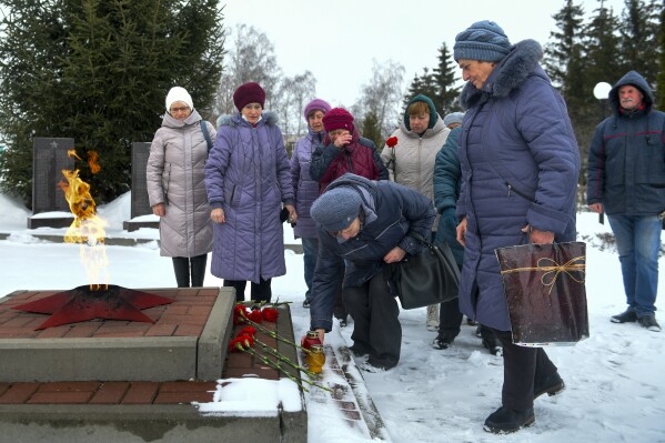 CAPTION CORRECTS LOCATION Women lay flowers in memory of those who were killed in the plane on Wednesday, at the memorial to soldiers who died in the Great Patriotic War "Enternal Flame", in Yablonovo, Belgorod region, Russia, Thursday, Jan. 25, 2024. A Russian military transport plane crashed in a border region near Ukraine. Moscow accused Kyiv of shooting it down and said that all 74 people aboard were killed on Wednesday. Russia said the fatalities included 65 Ukrainian POWs. (AP Photo)