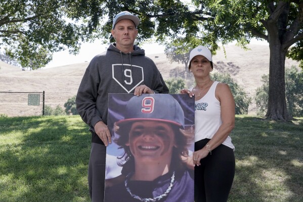 Padrig and Gina Fahey hold a photo of their son, Braden, 12, as they stand for a portrait in California on Wednesday, Sept. 6, 2023. Braden collapsed at football practice in August 2022 and died of a malformed blood vessel in the brain. The Faheys couldn鈥檛 understand how Braden鈥檚 face appeared on the cover of the book 鈥淐ause Unknown,鈥� which was co-published by an anti-vaccine group led by Robert F. Kennedy Jr., or why his name appeared inside it. (APPhoto/Godofredo A. V谩squez)