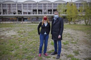 In this image provided by Budapest City Hall, Gergely Karacsony, Mayor of Budapest, right, and Krisztina Baranyi, the mayor of Budapest's 9th district, left, pose together for a photo at the planned site of the Chinese Fudan University campus in Budapest, Hungary on April 26, 2021.  Hungary's right-wing government envisions the construction of a gigantic university which has pledged its allegiance to the Chinese Communist Party, while others, like Karacsony and Baranyi, oppose the plan saying the project could have national security risks. (Budapest City Hall via AP)