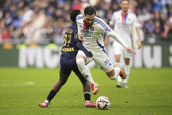 Lyon's Rayan Cherki, right, is challenged by Reims' Mamadou Diakhon during the French League One soccer match between Lyon and Reims at the Groupama stadium in Decines, outside Lyon, central France, Feb. 9, 2025. (AP Photo/Laurent Cipriani, File)