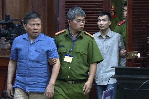 FILE - Australian man Chau Van Kham, left, is escorted into a court room in Ho Chi Minh city, Vietnam, Nov. 11, 2019. Chau Van Kham on Thursday, July 13, 2023, thanked his supporters who helped secure his release from a Vietnamese prison this week four years into a 12-year sentence for terrorism offenses. (Nguyen Thanh Chung/VNA via AP, File)