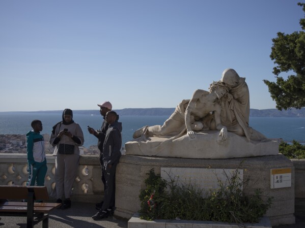 Visitors stand next to a statue depicting the passion of Christ at the Notre Dame de la Garde Basilica in Marseille, southern France, Friday, April 19, 2024. (AP Photo/Daniel Cole)