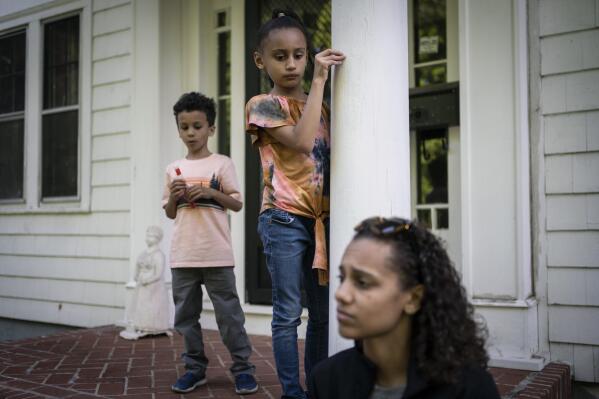 Catherine Manson sits on the front porch of her aunt's home as her children, Caydence Manson, center, and Carter Manson, play close by in Hartford, Conn., on Wednesday, May 25, 2022. About 4 million children in the United States, including Caydence and Carter, currently have asthma. But stark disparities exist: More than 12% of Black children nationwide suffer from the disease, compared with 5% of white children. (AP Photo/Wong Maye-E)