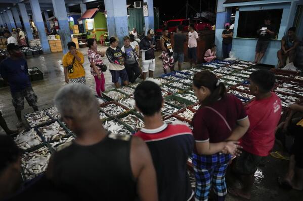 Buyers inspect fish at a market in Tacloban, Leyte, Philippines on Wednesday, Oct. 26, 2022. (AP Photo/Aaron Favila)