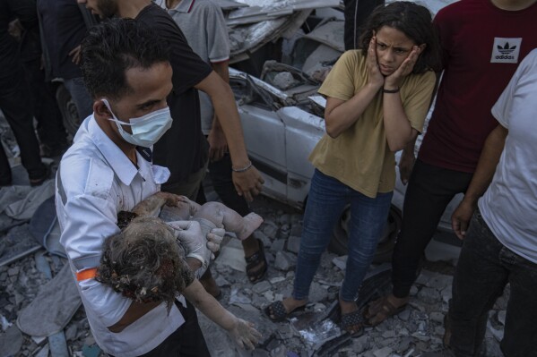 A Palestinian girl reacts as a child is carried from the rubble of a building after an airstrike in Khan Younis, Gaza Strip, Saturday, Oct. 21, 2023. (AP Photo/Fatima Shbair)