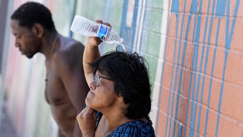Dos personas sin hogar tratan de protegerse del calor el 14 de julio de 2023, en Phoenix. (Foto AP/Matt York)
