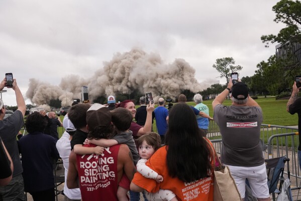 Tuff Gary, left, and Morgan LeBlanc with their children Hudson, Tuff, Jr., and Zander, of Jenning, La., watch the implosion of the Hertz Tower, that was heavily damaged after Hurricanes Laura and Delta in 2020, in Lake Charles, La., Saturday, Sept. 7, 2024. (AP Photo/Gerald Herbert)