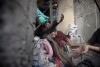 Palestinians try to rescue a woman stuck under the rubble of a destroyed building following Israeli airstrikes in Khan Younis refugee camp, southern Gaza Strip, Thursday, Dec. 7, 2023. In recent days, Israeli tanks have rumbled into southern Gaza, starting with Khan Younis. (AP Photo/Mohammed Dahman)