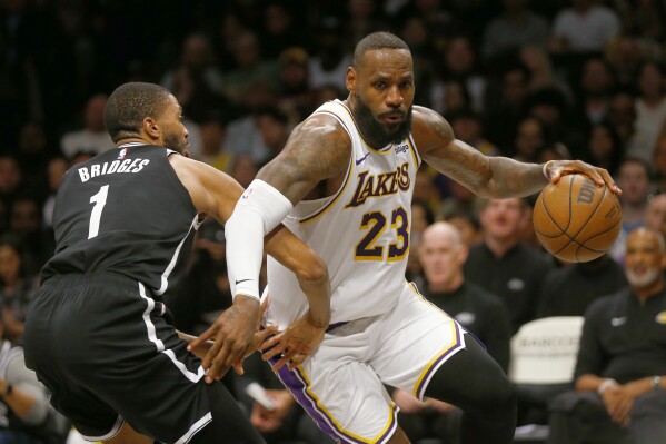 Los Angeles Lakers forward LeBron James (23) drives around Brooklyn Nets guard Mikal Bridges (1) during the first half of an NBA basketball game Sunday, March 31, 2024, in New York. (AP Photo/John Munson)