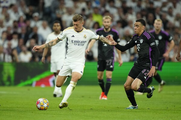 Real Madrid's Toni Kroos, left, challenges for the ball with Bayern's Jamal Musiala during the Champions League semifinal second leg soccer match between Real Madrid and Bayern Munich at the Santiago Bernabeu stadium in Madrid, Spain, Wednesday, May 8, 2024. (Ǻ Photo/Jose Breton)