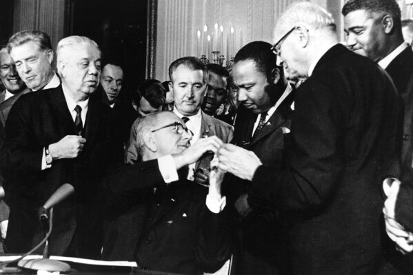 In this July 2, 1964, file photo, President Lyndon B. Johnson reaches to shake hands with Dr. Martin Luther King Jr. after presenting the civil rights leader with one of the 72 pens used to sign the Civil Rights Act in Washington. Surrounding the president, from left, are, Rep. Roland Libonati, D-Ill., Rep. Peter Rodino, D-N.J., Rev. King, Emanuel Celler, D-N.Y., and behind Celler is Whitney Young, executive director of the National Urban League. President Barack Obama was 2-years-old when Johnson signed the Civil Rights Act. Half a century later, the first black president will commemorate whatÕs been accomplished in his lifetime. HeÕll also recommit the nation to fighting deep inequalities that remain.  (ĢӰԺ Photo)