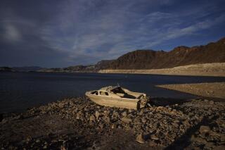 FILE - A formerly sunken boat sits high and dry along the shoreline of Lake Mead at the Lake Mead National Recreation Area, Tuesday, May 10, 2022, near Boulder City, Nev. Authorities in Las Vegas say they've identified human remains found in October 2022 at shrinking Lake Mead as a North Las Vegas man who drowned in April 1974. The Clark County coroner's office said Tuesday, March 28, 2023, that Donald P. Smith was 39 when he was reported missing in the waters of the Colorado River reservoir behind Hoover Dam. (AP Photo/John Locher,File)