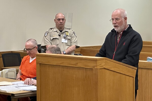 Gene Keyes, right, speaks to a judge in Howell, Mich., Friday, May 10, 2024, about the death of his mother from a tainted steroid injection in 2012. Specialty pharmacy executive Barry Cadden, left, was sentenced to at least 10 years in prison for the deaths of 11 people who were injected with tainted pain medication, part of a meningitis outbreak that affected hundreds across the U.S. in 2012. (AP Photo/Ed White)